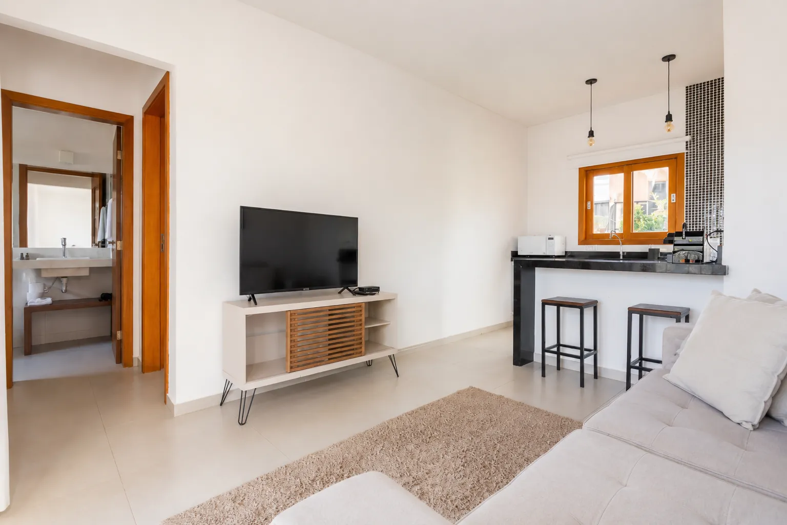 Sala do apartamento térreo com TV e cozinha integrada